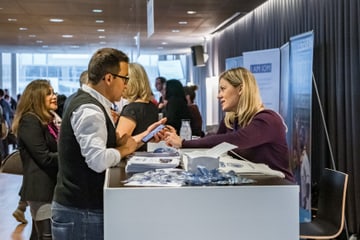 People conversing at a booth during a conference.
