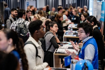 Room at the Job Fair of Forum cinfo 2024 with people interacting at tables. Room with people interacting at tables.