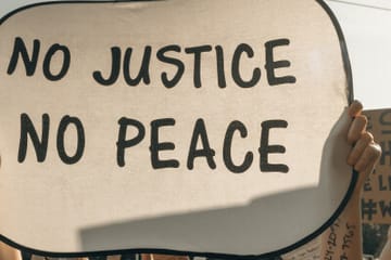 people demonstrating and holding up a sign: "no justice no peace"