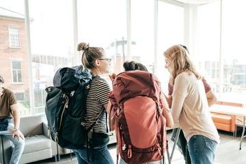 Group of backpackers talking in a bright room.