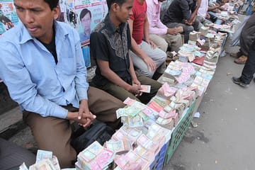 Men exchanging money sitting on the side of a road 