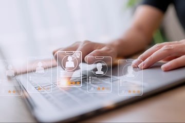 Hands typing on laptop with digital profile icons overlay.